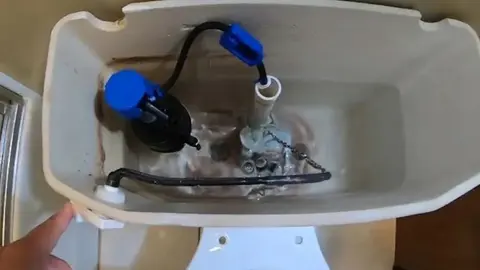Open toilet tank showing the fill valve, float and flapper assembly